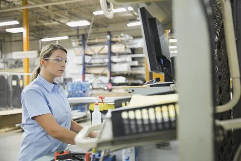 Female worker using computer in factory Foto stock