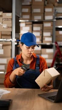 Female worker in warehouse using bar code scanner to scanning box sitting a.. Foto stock
