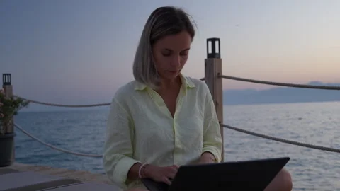 Female is working on a computer at the beach. Stock Footage 282237452