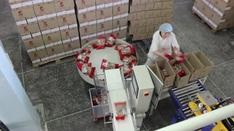 A female working packer puts Packed sweet bars in boxes at a candy factory. Stock Footage 128643281