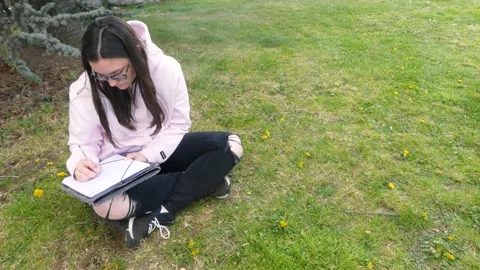 Female writer using a pen to write on a paper sheet while sitting on Stock Footage 196991284