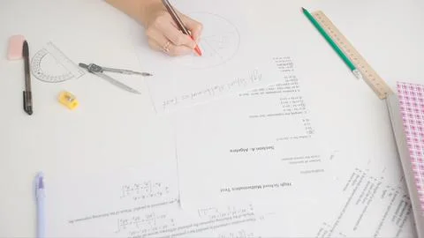 Female writes correct answer in geometry exam test paper with pen. Student Stock Photos