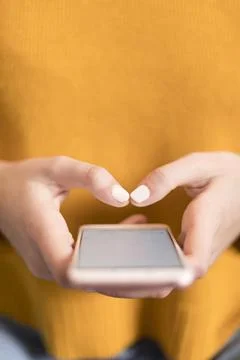 Female in a yellow pullover, using smartphone Stock Photos