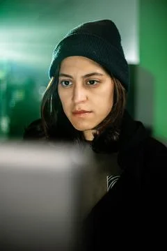 Female young hacker working on computer in dark room programming code 库存照片