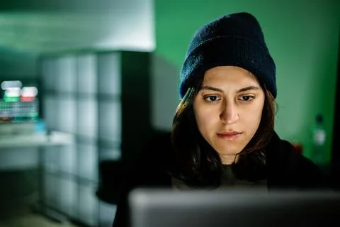 Female young hacker working on computer in dark room programming code Stockfoto's