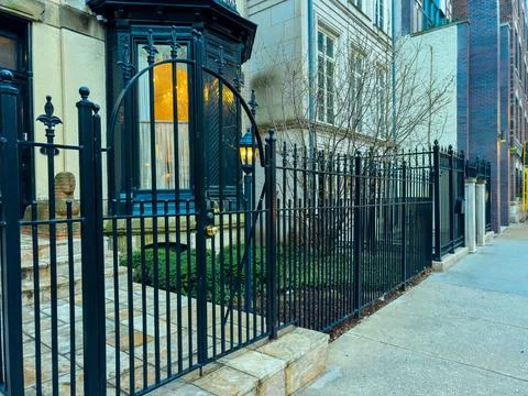 Fence and gate in front of a building on a city street during evening Stock Photos