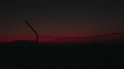 Fence with barbed wire on a background of sunset and night sky. 库存影片 132632880