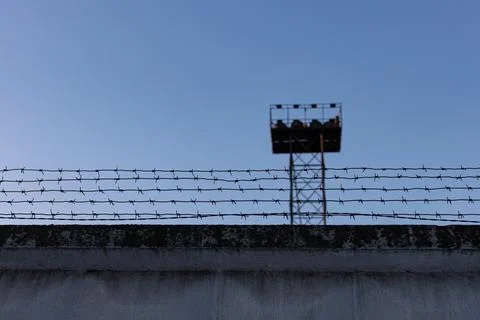Fence with barbed wire behind which there is a tower Stock Photos