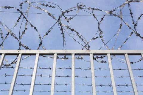 Fence with barbed wire on the border of the object Stock Photos