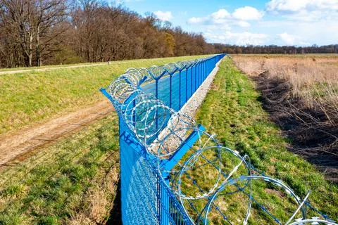 Fence with barbed wire at a guarded facility, it is dangerous to enter Stock Photos