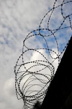 Fence with barbed wire on the top of a wall Stock Photos