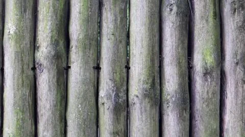 The fence is built of logs. Gray background. Rough logs wall vertical backgro Stock-Fotos