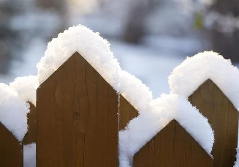 Fence covered with snow in the sunlight Stock Photos