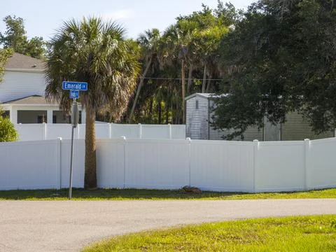 Fence in Florida backyard. White plastic fencing from vinyl planks for ground Stock Photos