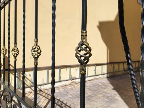 A fence with forged bronze elements on the background of a beige wall of the  Stock Photos