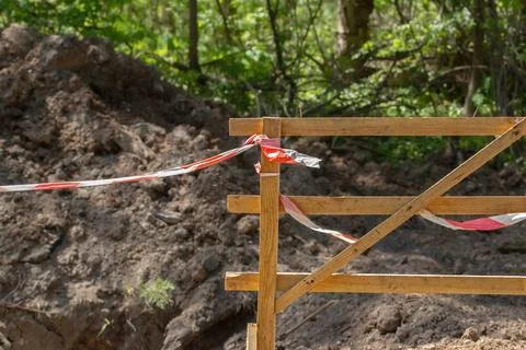 Fence in front of a pit on the road with warning tape for motorists. Stock Photos