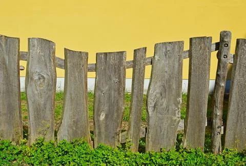 A fence made of old boards on the background of a yellow wall Stock Photos