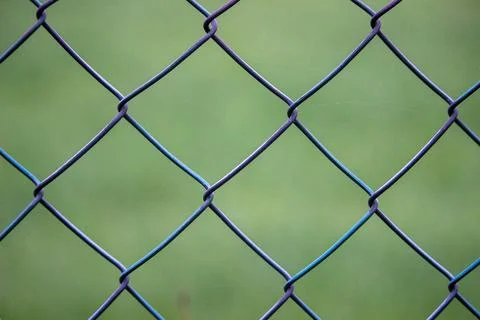 Fence made out off wire close up with out of focus grass in the background Stock Photos