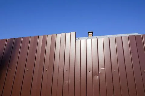 A fence made of profiled metal sheet against a blue sky Stock Photos