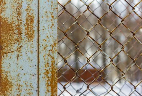 The fence is made of rusty chain-link mesh. Stock Photos