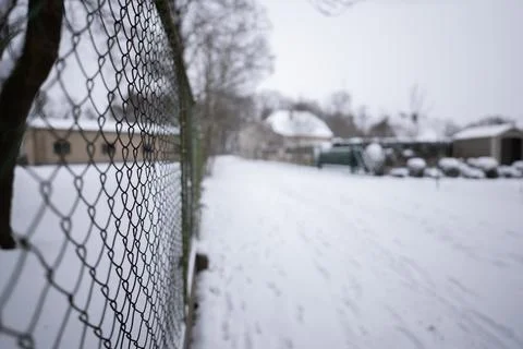 Fence mesh escaping along frame into blur on cloudy winter day Foto stock
