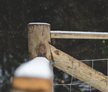 Fence post in corner with falling snow 스톡 사진