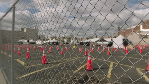 Fence pov of vacant covid testing site in nyc parking lot Vídeo Stock 251192424