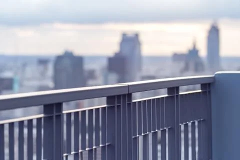 Fence on skyscraper rooftop with city background at sunset Stock Photos