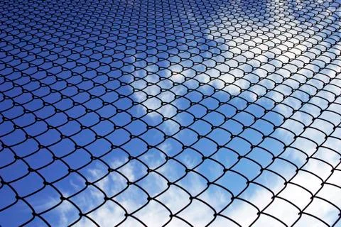 The fence of wire netting on the background of blue sky Stock Photos
