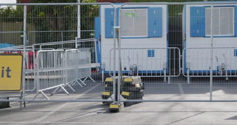 Fenced off area of an NHS COVID-19 walk-through test centre with cabins behind Stock Footage 149222559
