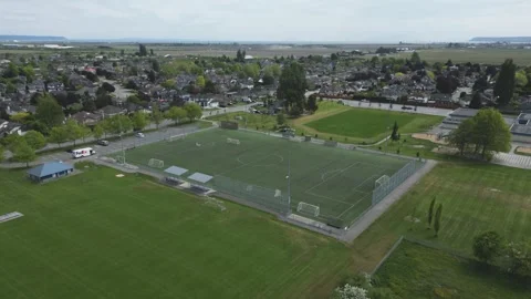 Fenced artificial turf soccer field sits adjacent to green municipal parks Stock Footage 337735470
