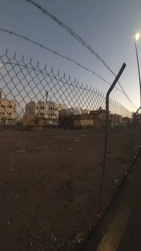 Fenced Empty Lot and City Buildings at Twilight Stock Footage 346534673