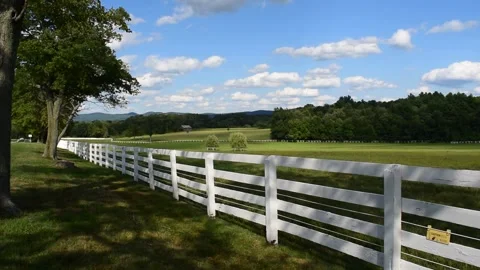 Fenced meadow with blue skies and mountains in the distance (wide view) Stock Footage