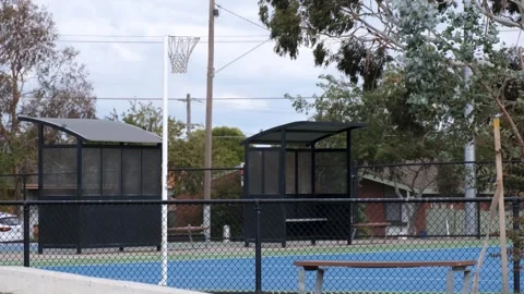 Fenced outdoor netball court with player shelters in suburban Australia Vídeos de archivo 336034853