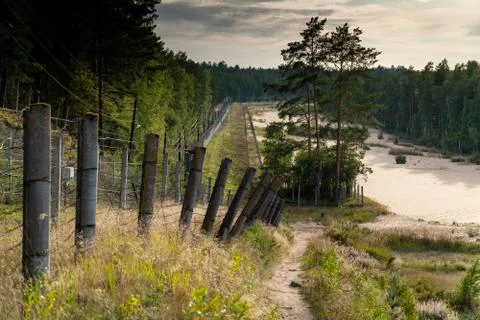 Fences of rows of barbed wire , going into the distance, on the shore of the Stock Photos