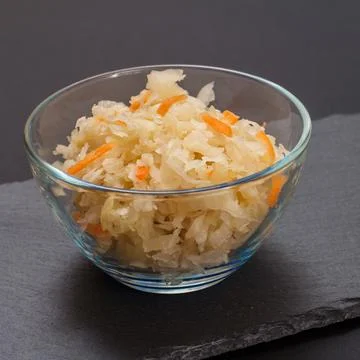 Fermented cabbage with herbs and spices in glass bowl on the black background Stock Photos