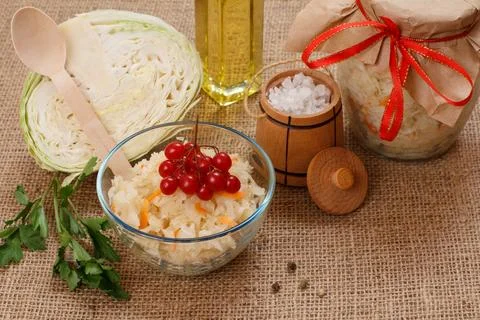 Fermented cabbage with herbs and spices in glass bowl and jar on the black .. Stock Photos
