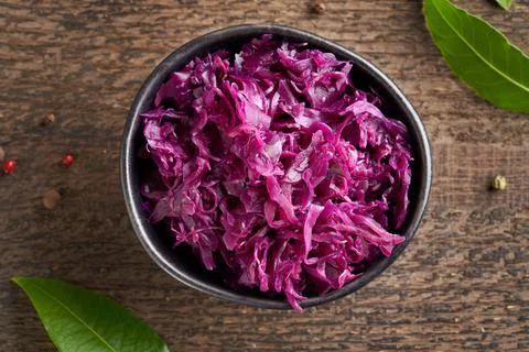 Fermented red cabbage in a bowl on a table, top view Stock Photos