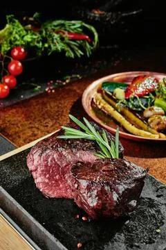Fermented steak. Grilled steak medium with grilled vegetables on black plate on Stock Photos