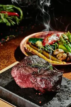 Fermented steak. Grilled steak medium with grilled vegetables on black plate on Stock Photos