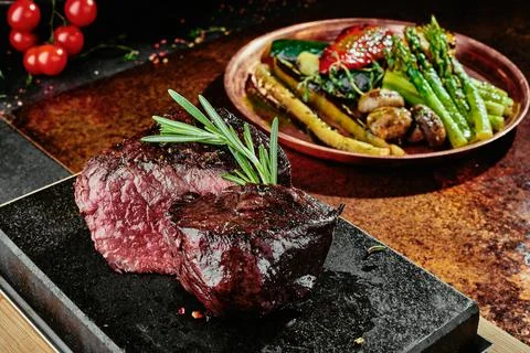 Fermented steak. Grilled steak medium with grilled vegetables on black plate on Stock Photos