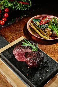 Fermented steak. Grilled steak medium with grilled vegetables on black plate on Stock Photos