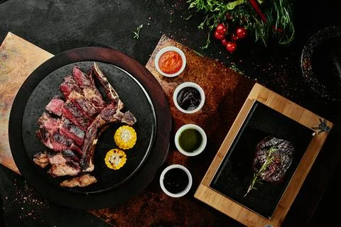 Fermented steak. T-Bone Steak with grilled vegetables on a black round plate on Stock Photos