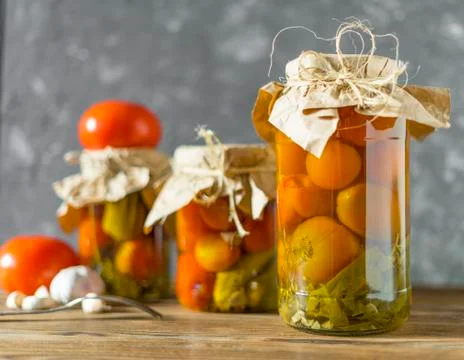 Fermented tomatoes on a rustic old vintage and grunge table with dark background Stock Photos
