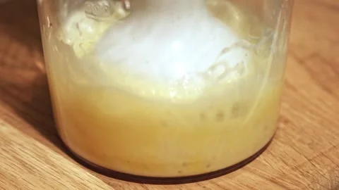 Fermenting dough starter in glass container on wooden surface Stock Footage 345262816