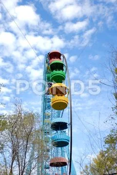 Ferris wheel against trees and the sky with clouds Stock Photos