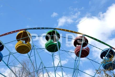 Ferris wheel against trees and the sky with clouds Stock Photos