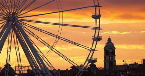 Ferris Wheel and illuminations in amusement park during scenic sunset clouds Stock Footage 217560998