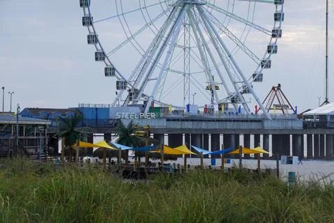 Ferris wheel and other amusements on a pier over the beach and ocean  Stock Photos