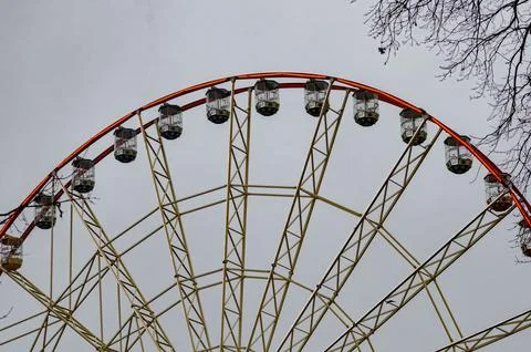 Ferris wheel behind bare trees in winter against grey sky Foto stock